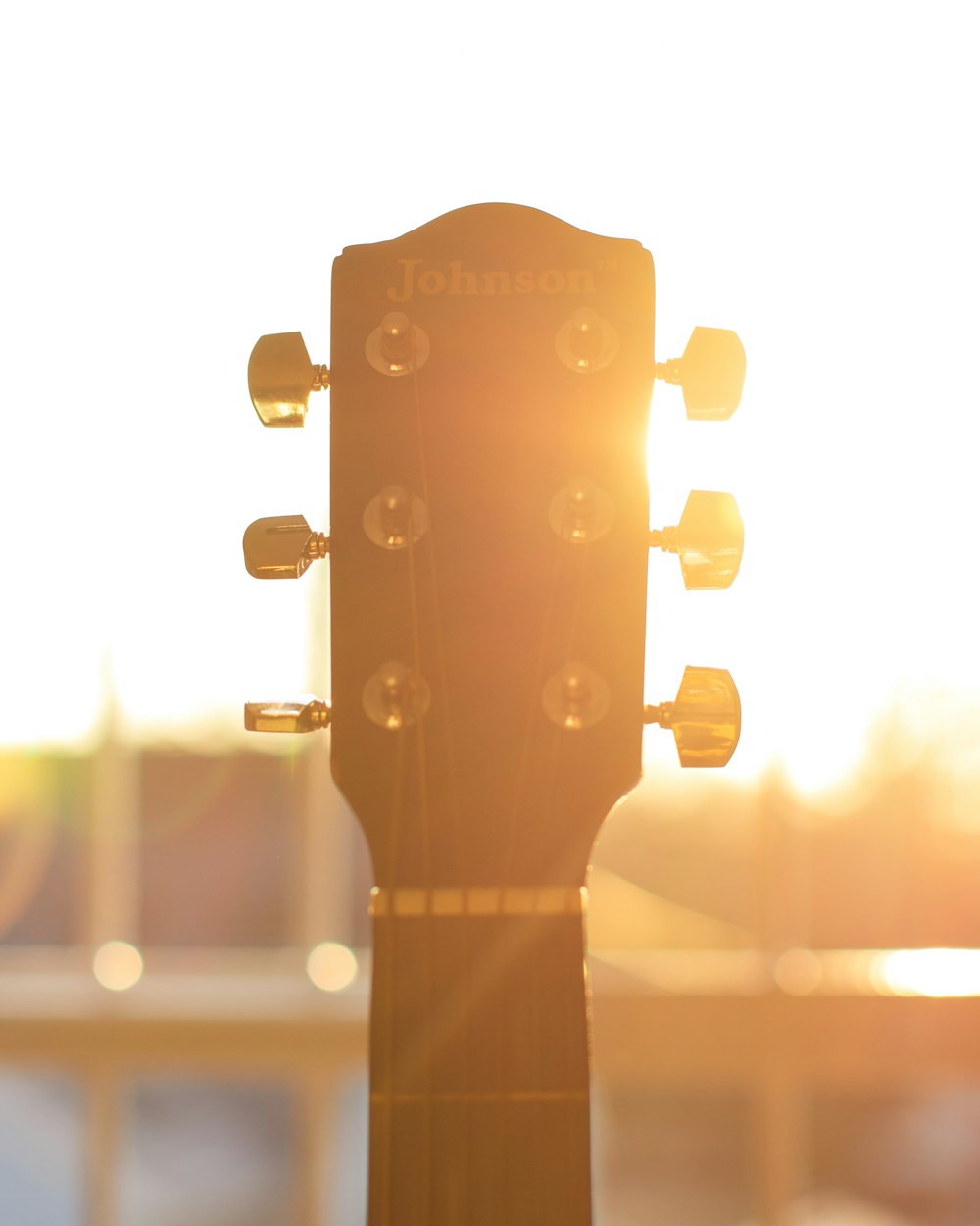 a close up of a guitar neck with the sun in the background