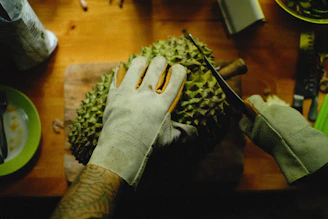 a person cutting a durian fruit on a cutting board