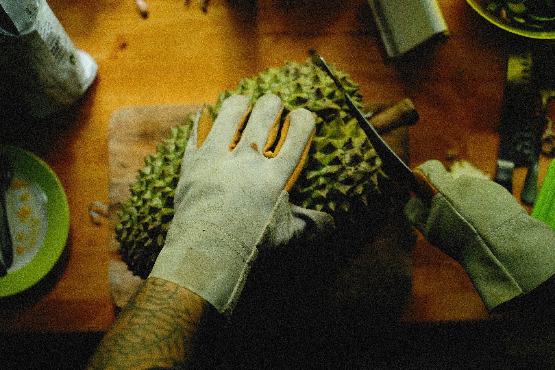 a person cutting a durian fruit on a cutting board