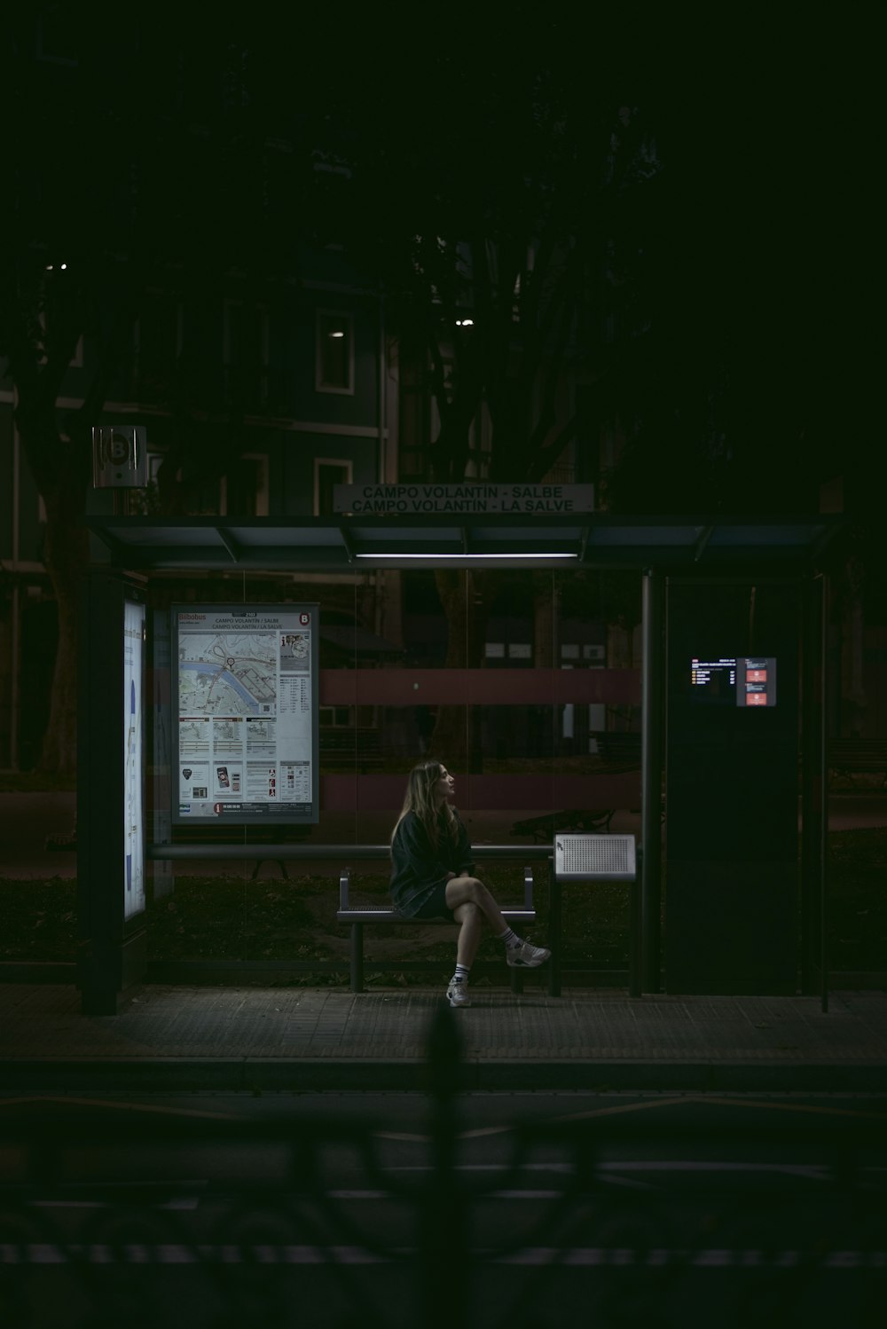 a woman sitting on a bench in the dark