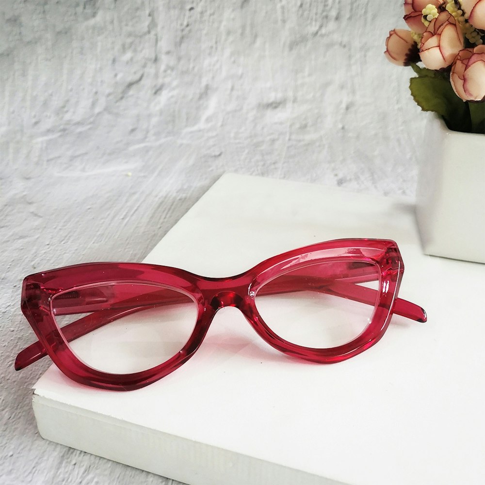 a pair of red glasses sitting on top of a white surface