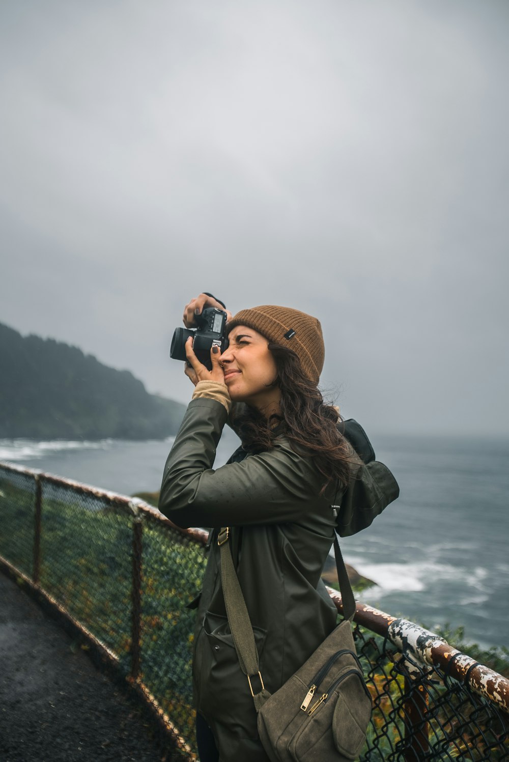 a woman taking a picture of the ocean with a camera