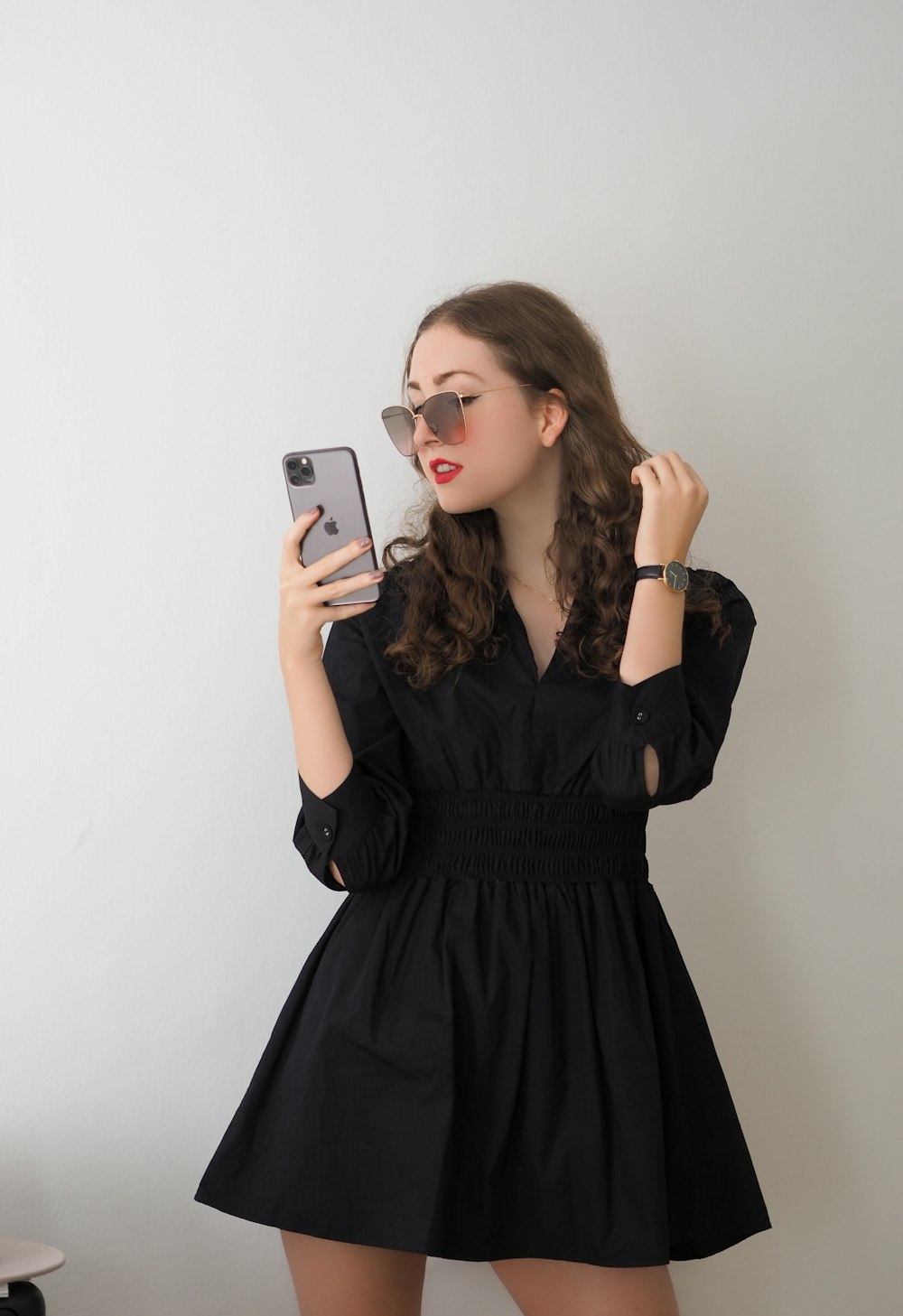 a woman in a black dress holding a cell phone