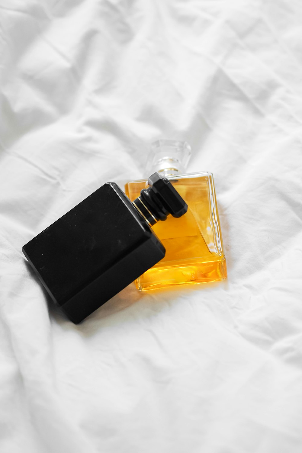 a bottle of cologne sitting on top of a white sheet