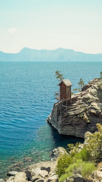 Modern wooden cabin with large windows overlooking a serene lake.