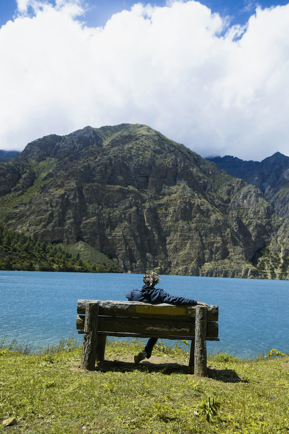 a person sitting on a bench in front of a lake
