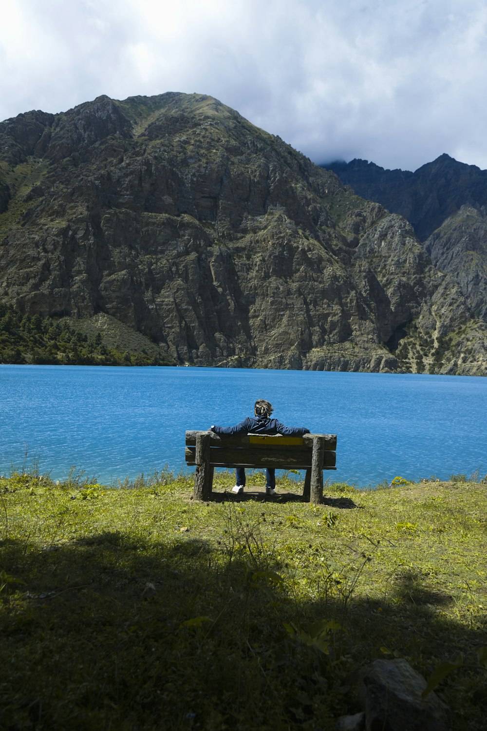 a man sitting on a bench in front of a lake