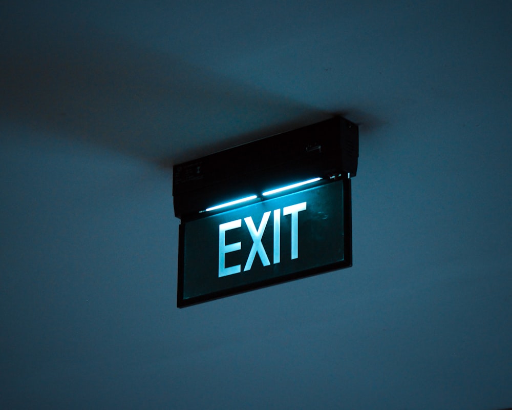 a green exit sign hanging from the ceiling