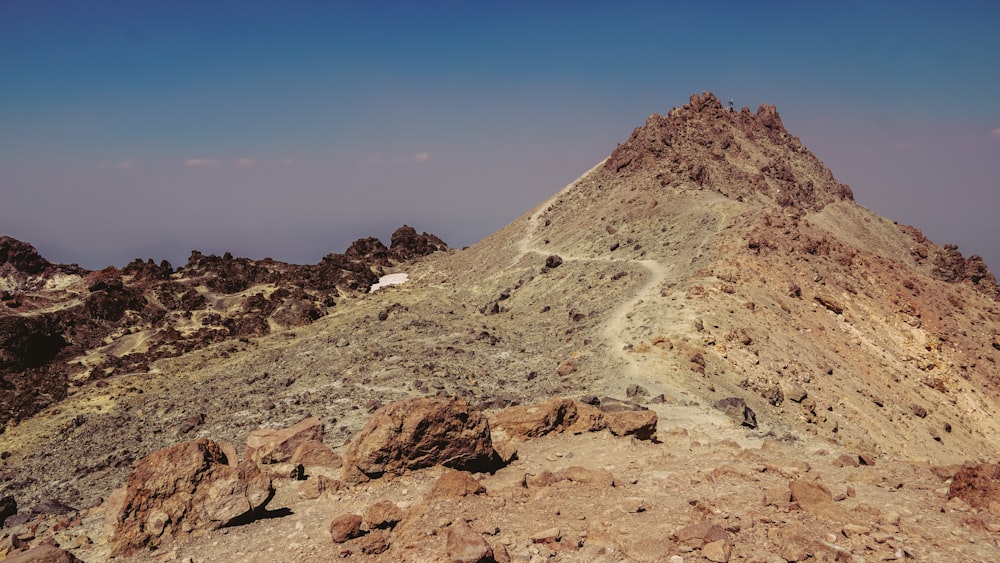 a rocky mountain with a small white building on top