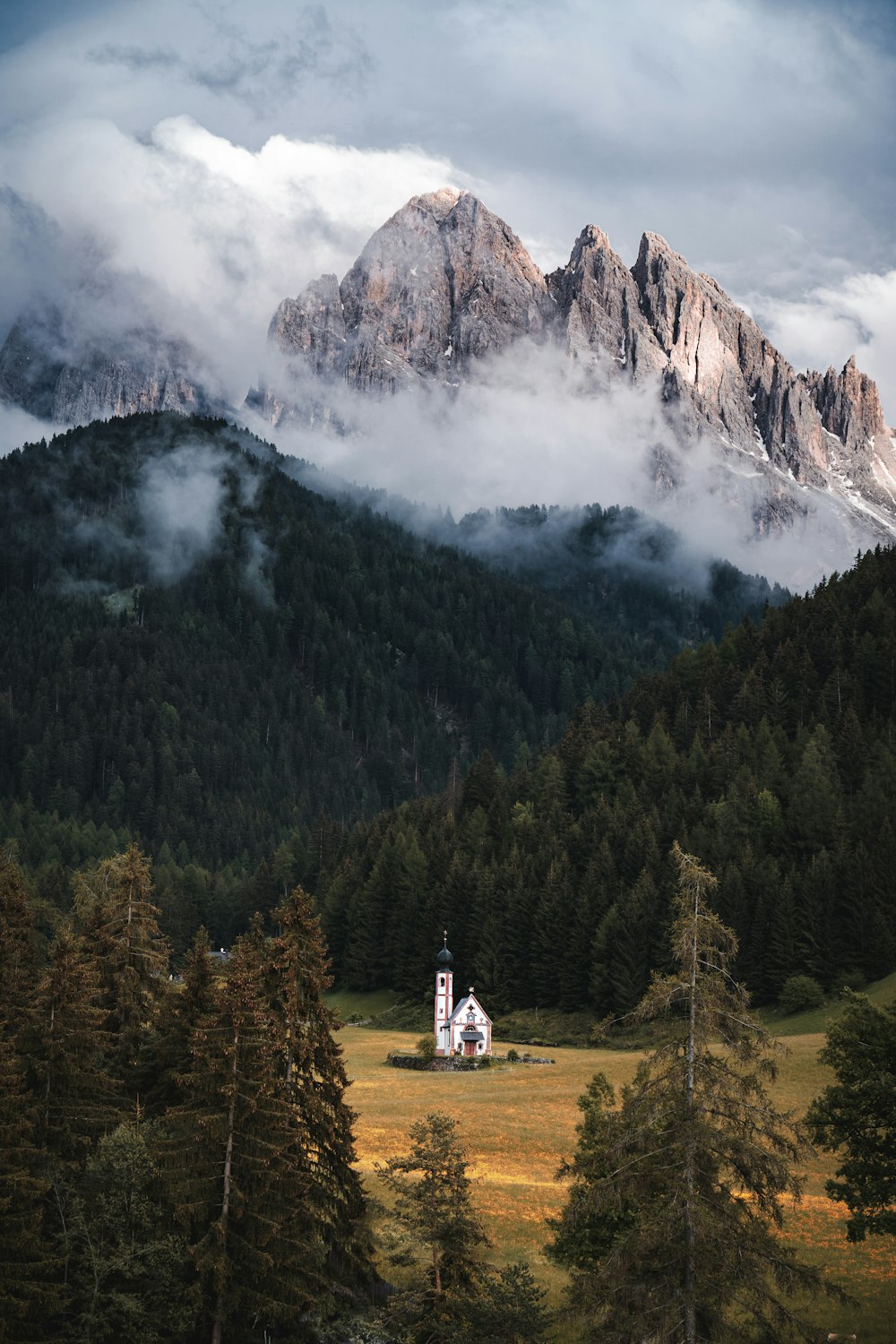 a church in the middle of a field with mountains in the background