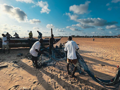 Fishermen working on a boat at Fidjrossè beach in Cotonou, Benin