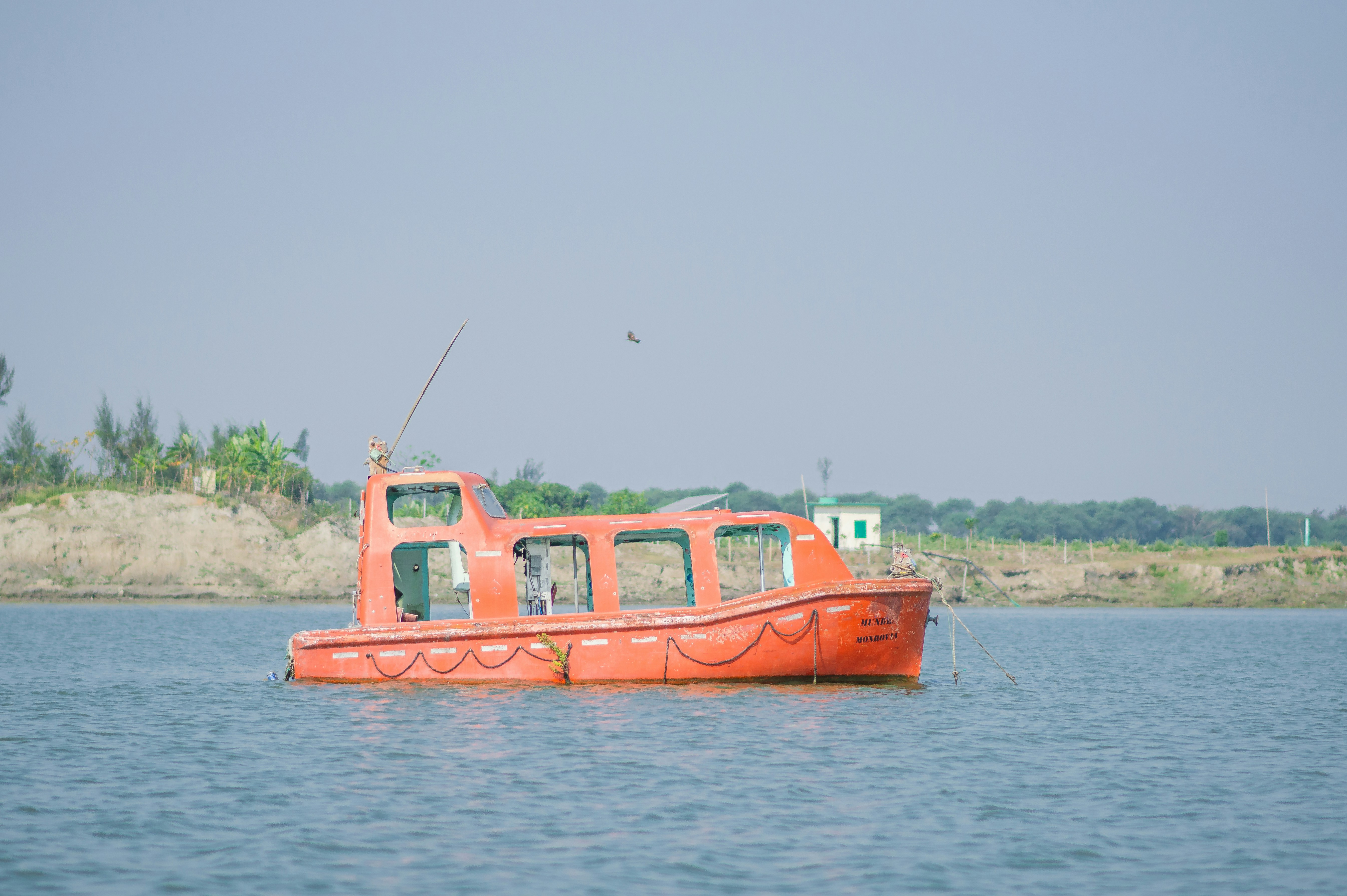 a red boat floating on top of a body of water