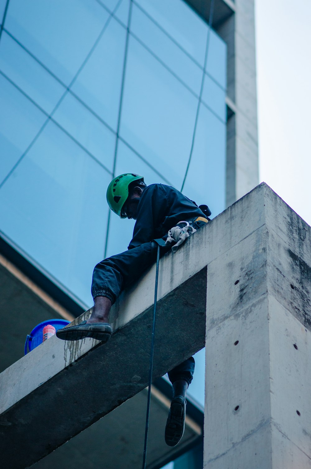 a man in a green helmet is climbing up the side of a building
