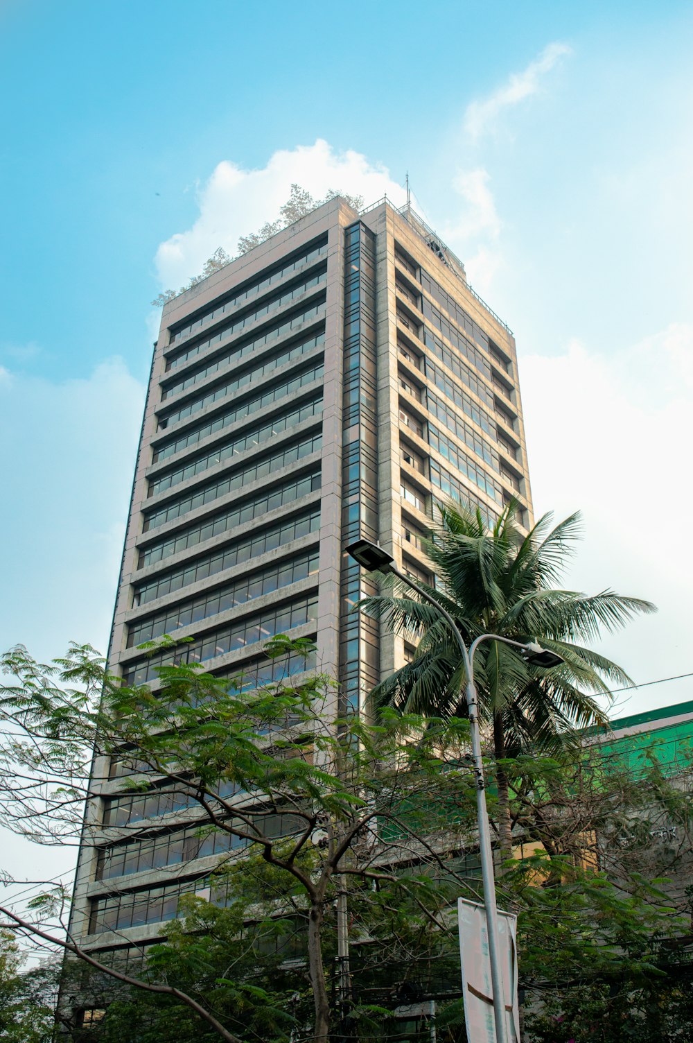 a tall building sitting next to a lush green forest