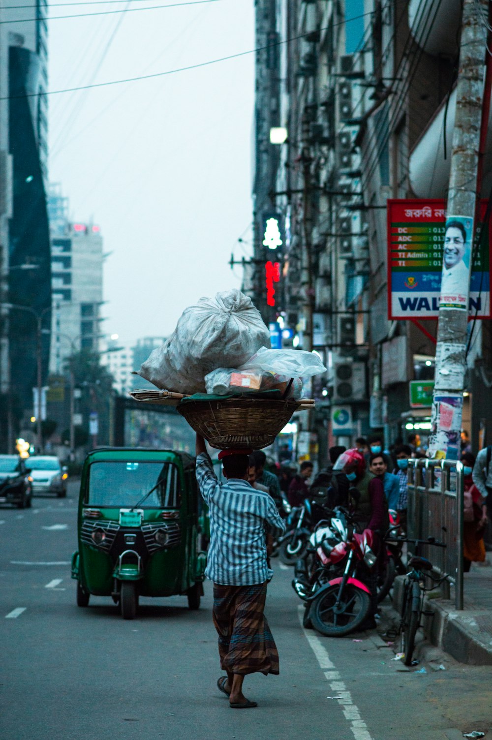 a woman walking down a street carrying a basket on her head