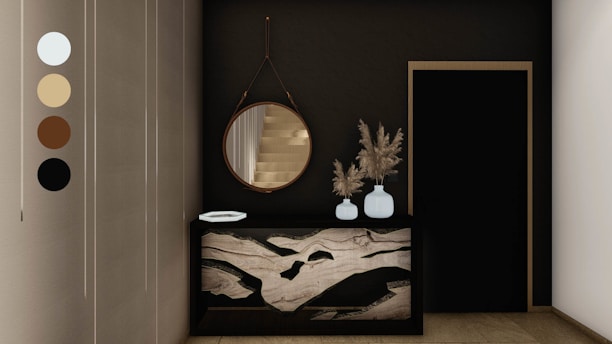 An elegant and modern interior space featuring a dark wall with a round mirror hanging above a decorative console table. The table has a unique marble design and holds two white vases filled with dried pampas grass. Next to it is a black door with a simple frame. Neutral tones are present, accentuated by the sleek design elements.