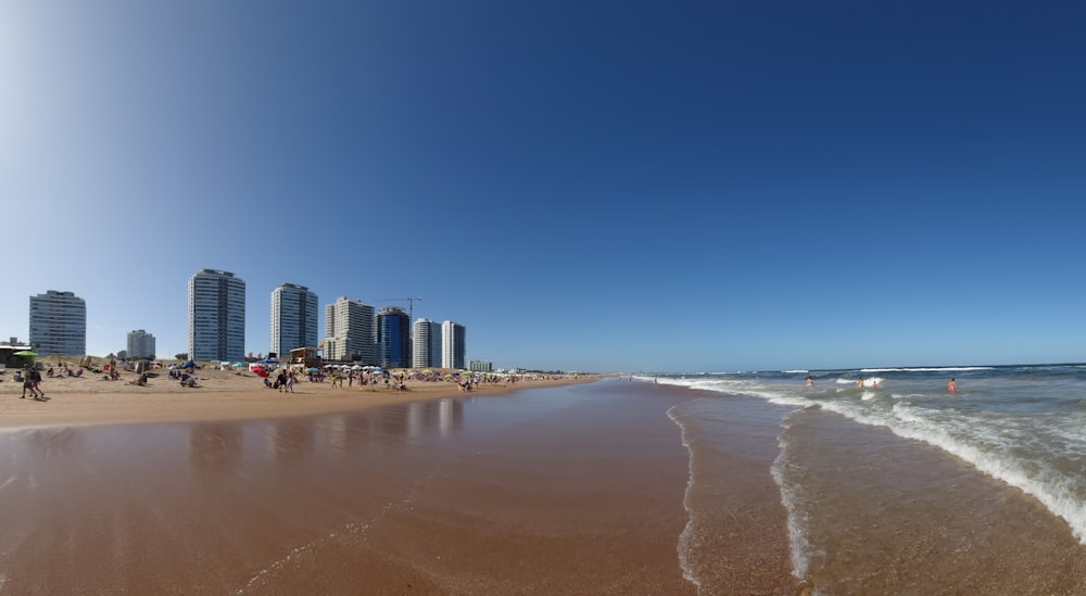 a beach with people walking on it and buildings in the background
