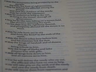 The image depicts a close-up of a page with printed text. The text appears in two columns, with a section of bullet points or numbered lines on the left. The page contains a passage likely from a religious or literary book, with a faint heading at the top.