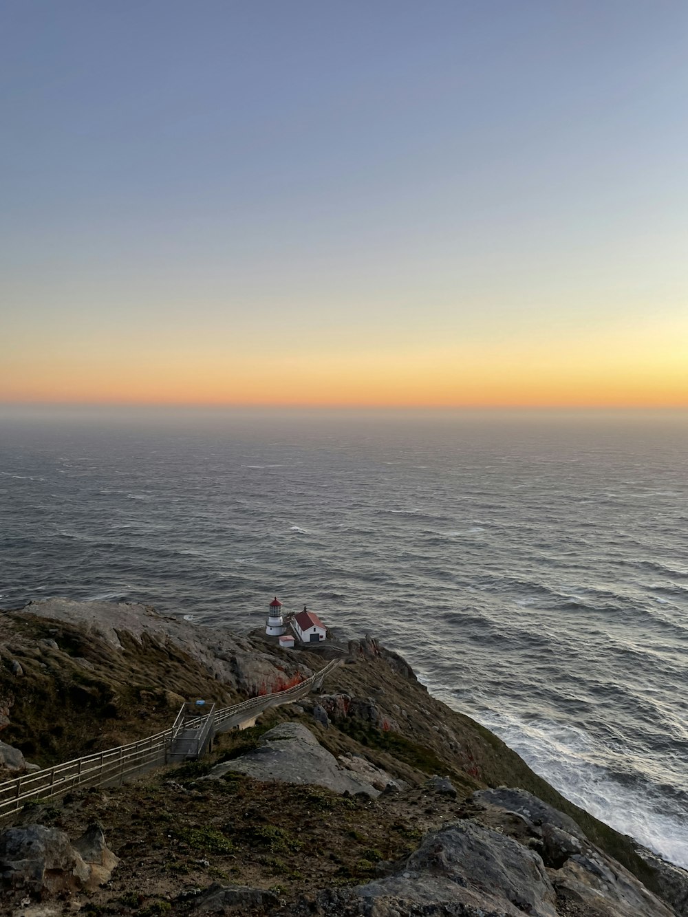 a lighthouse sitting on top of a cliff next to the ocean