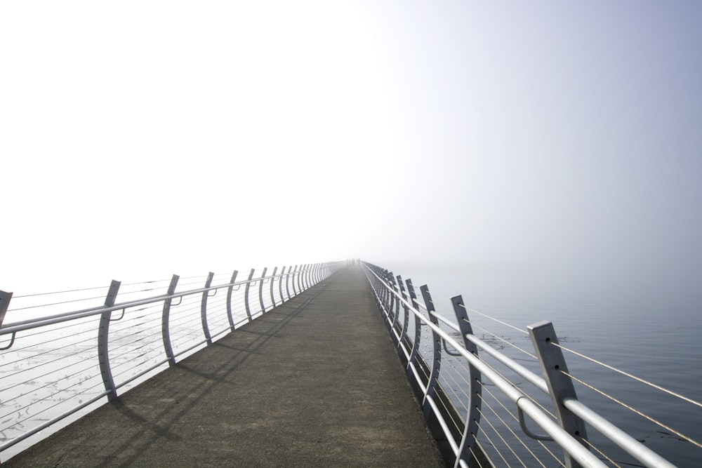 a foggy day on a bridge over a body of water