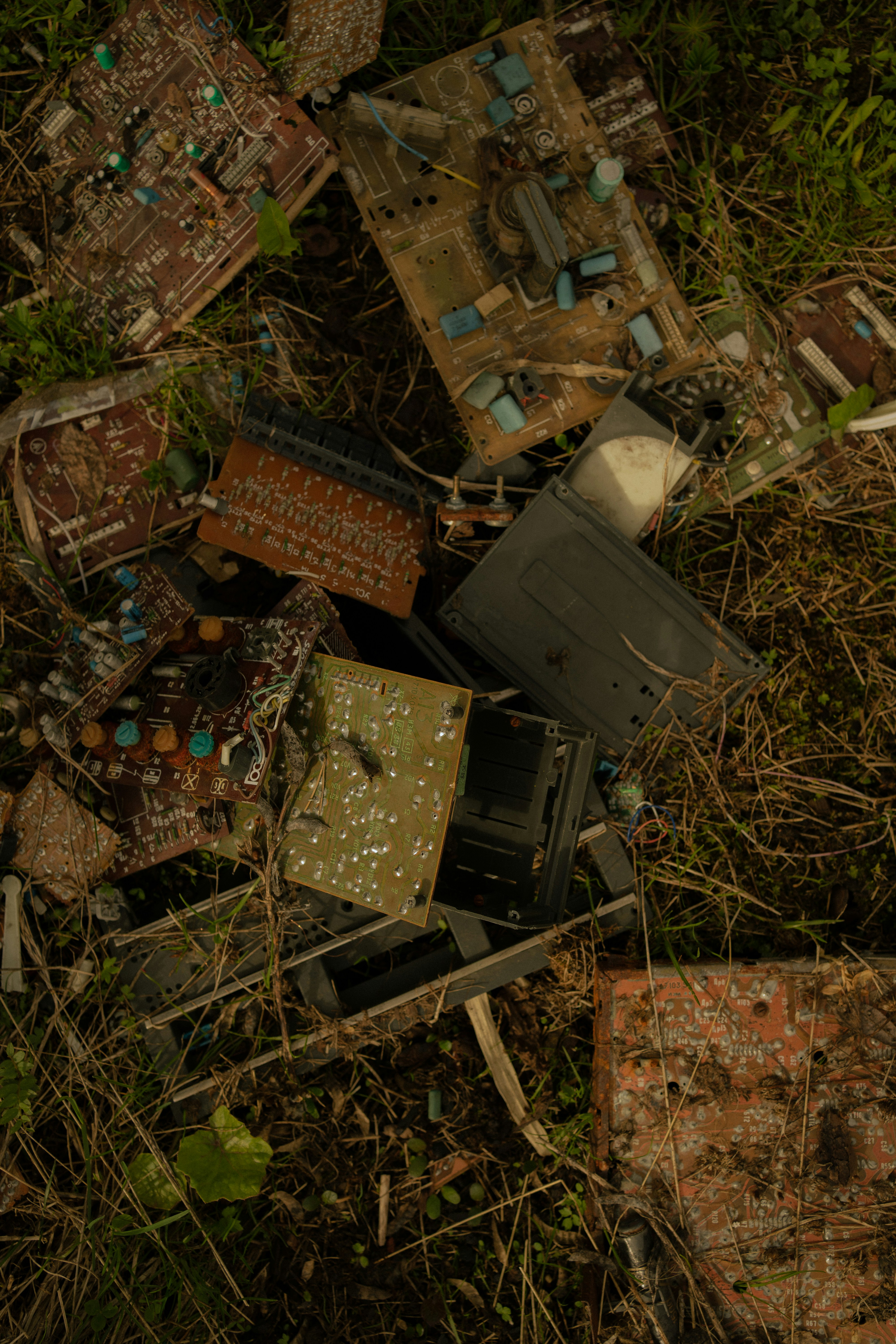 a pile of old broken electronics in the grass