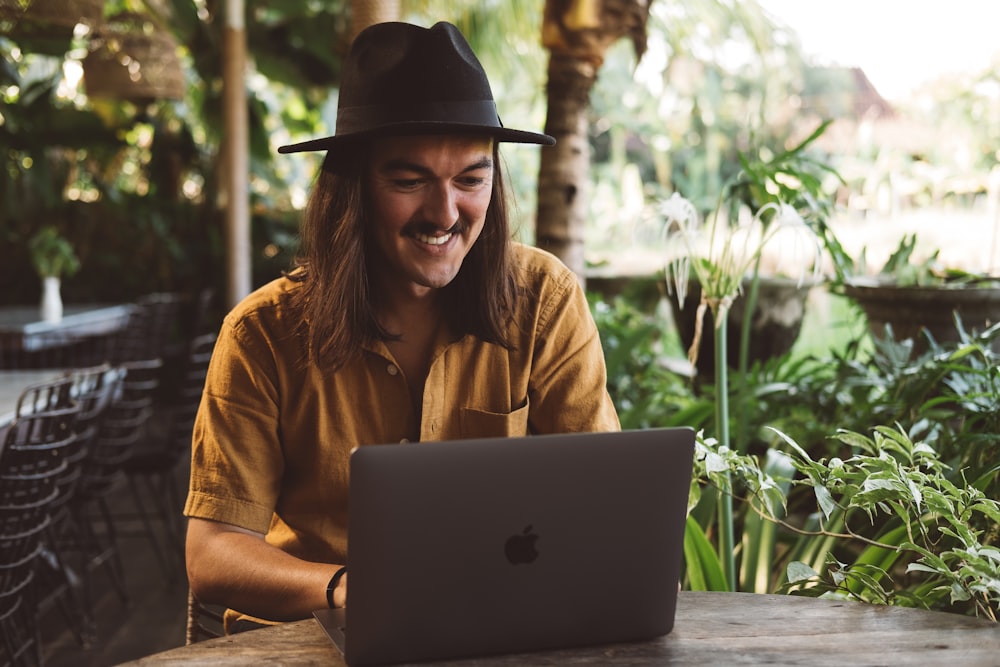 a man wearing a hat is looking at a laptop