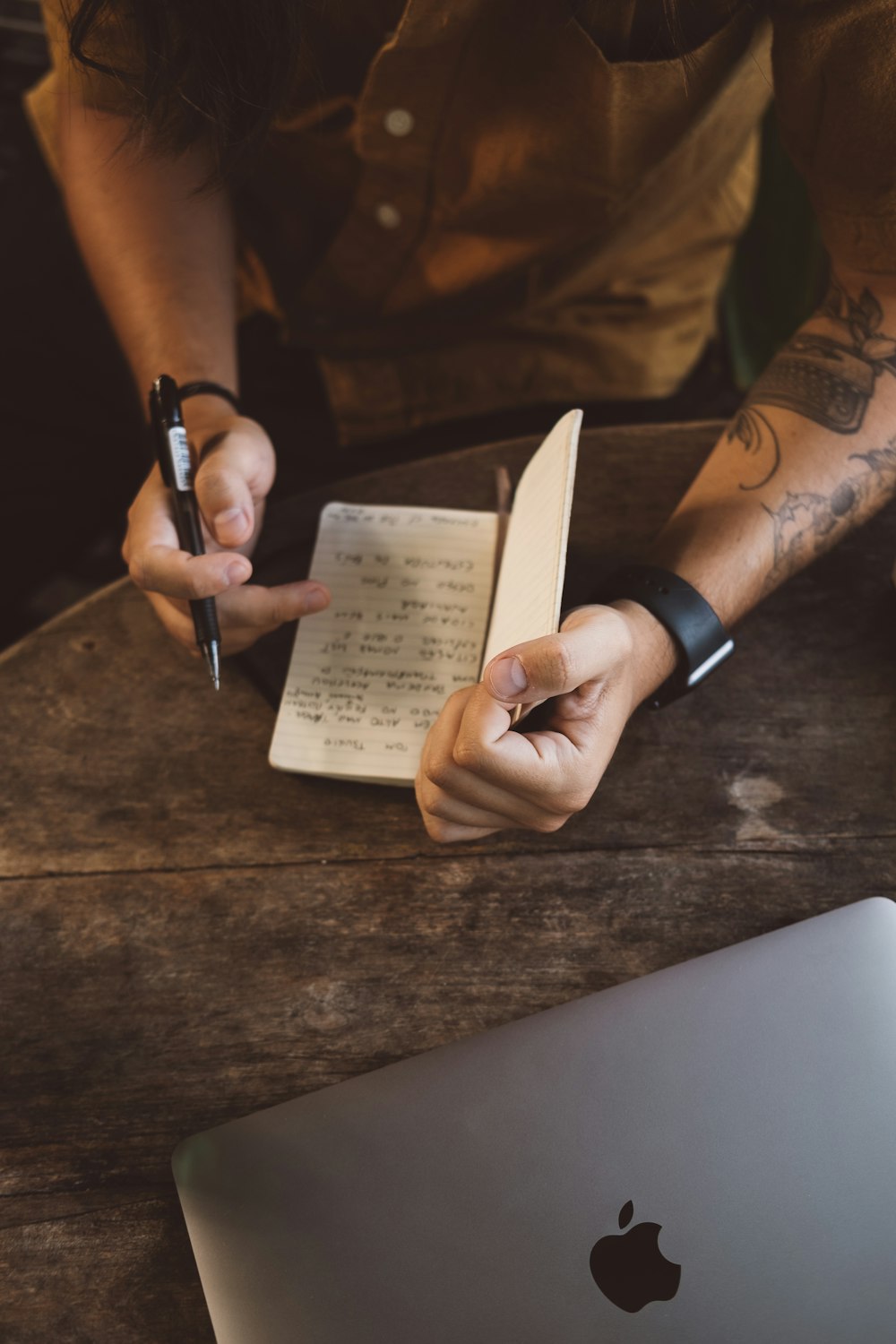 a person sitting at a table with a notebook and a pen