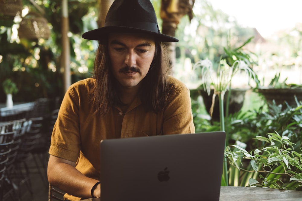 a man wearing a hat and using a laptop