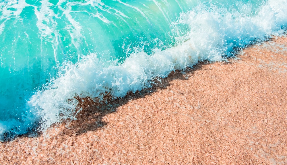 an aerial view of a wave crashing on a sandy beach