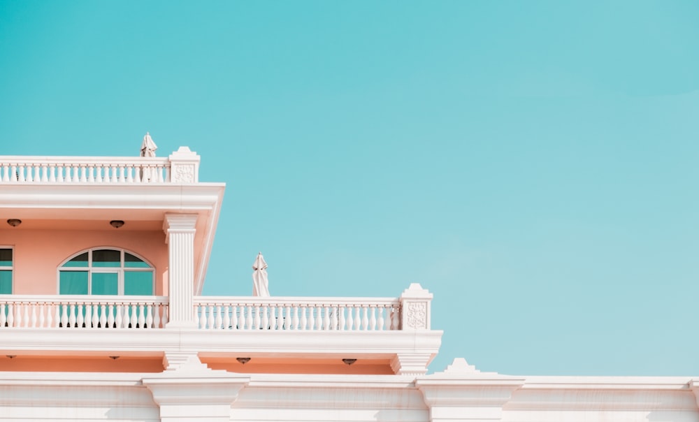 a pink and white building with a balcony and balconies