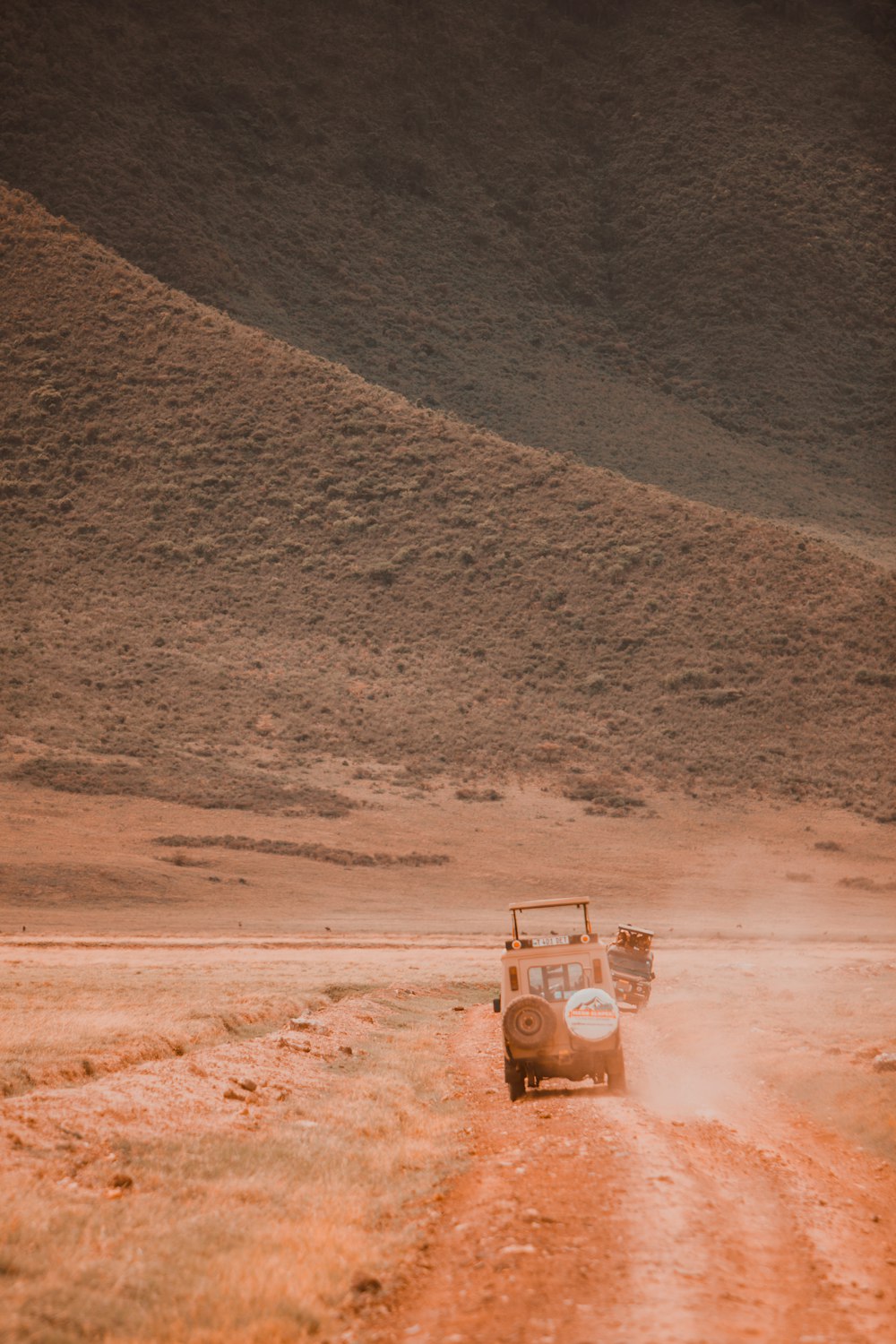 a car driving down a dirt road in the desert