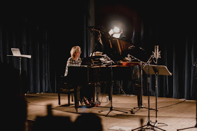 Kay performing passionately on stage with a grand piano under warm lights.