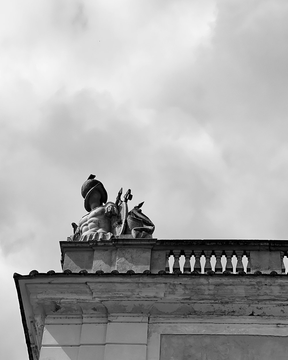 a black and white photo of a statue on top of a building