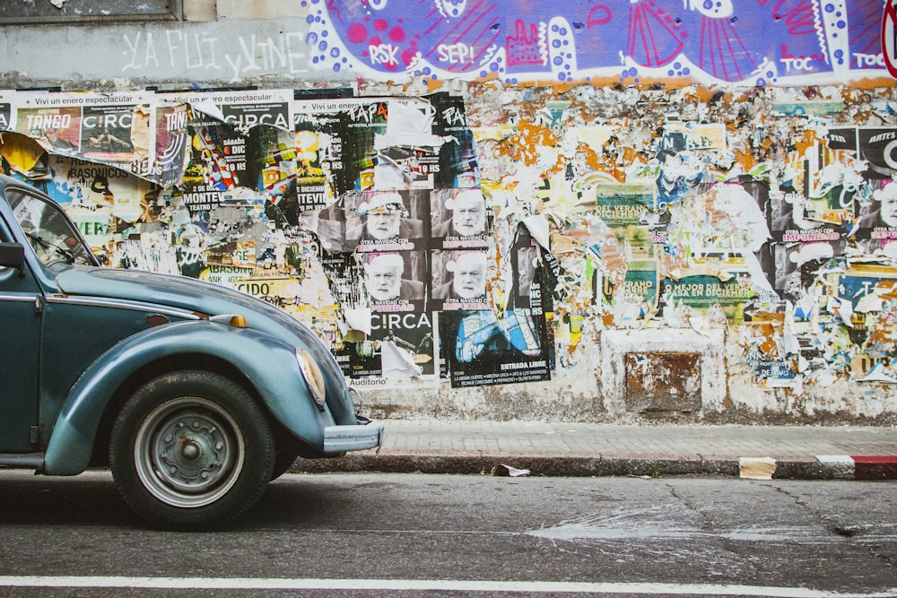 Un'auto blu parcheggiata davanti a un muro coperto di graffiti