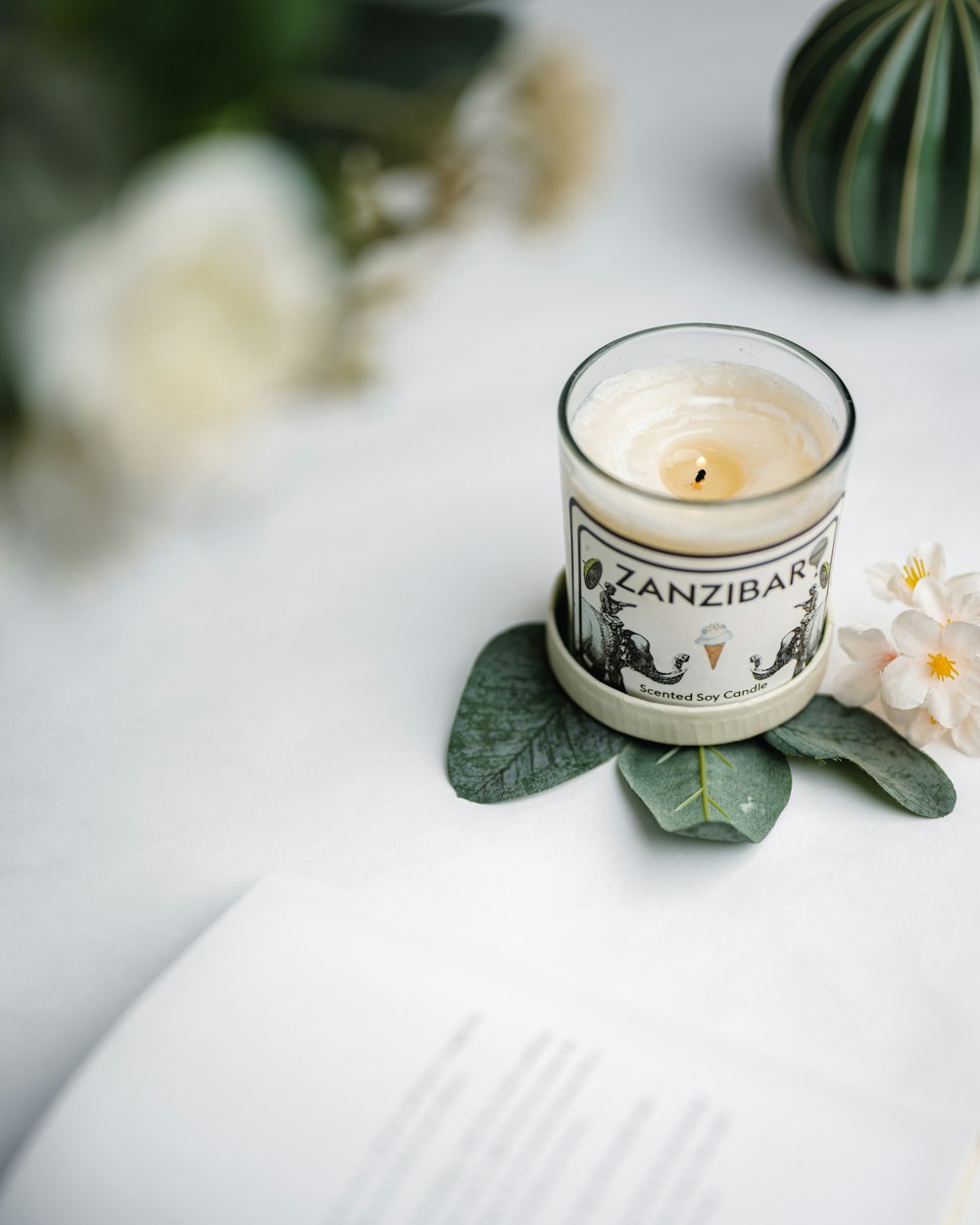 une bougie posée sur un livre à côté d’une fleur