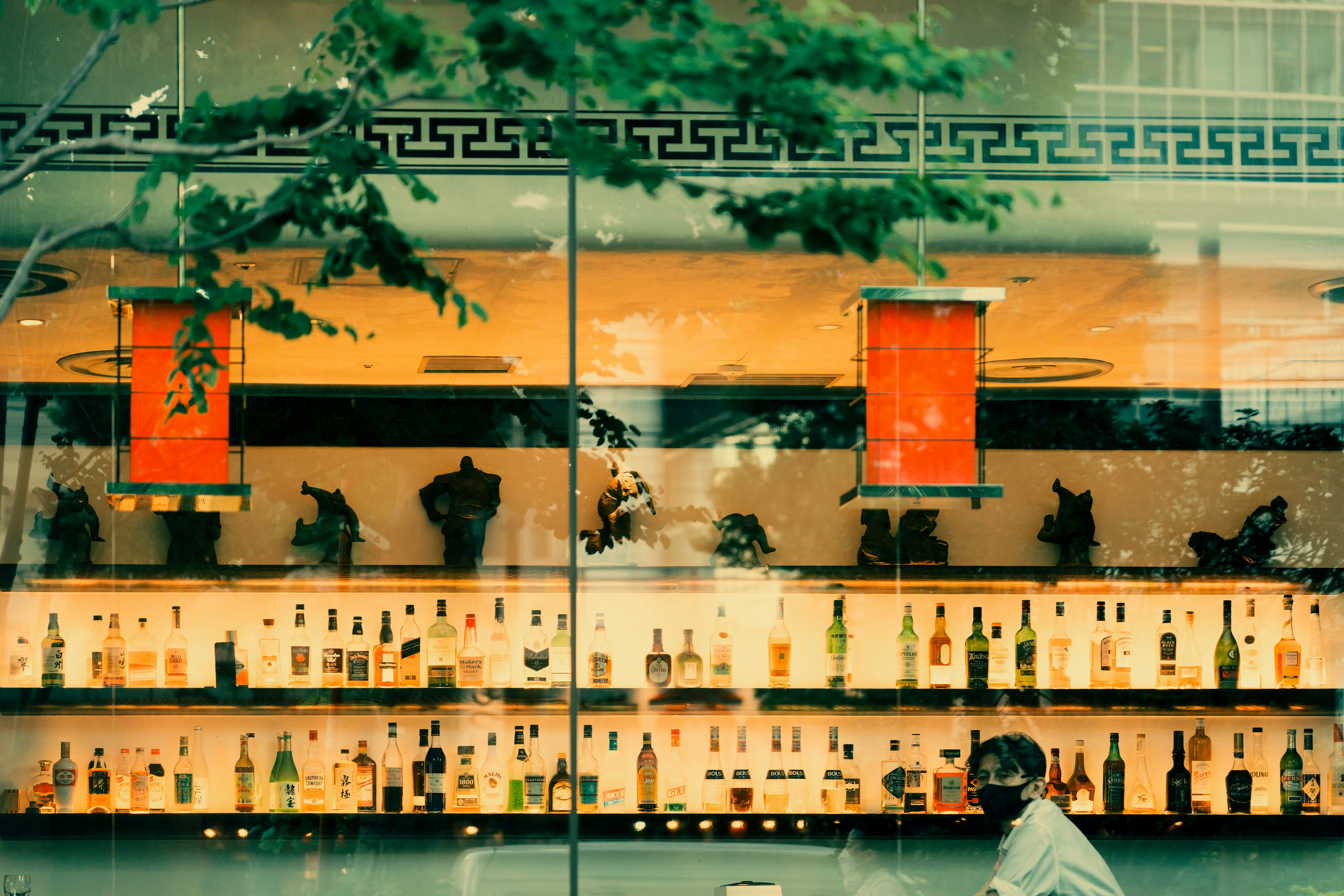 a man sitting in front of a bar filled with bottles