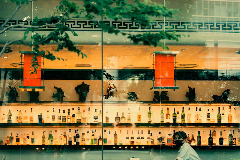 a man sitting in front of a bar filled with bottles