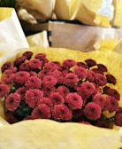 Close-up of a delicate bouquet with deep red Ecuadorian roses wrapped in elegant brown paper.