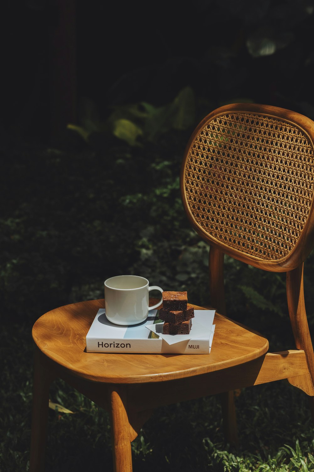 une chaise en bois avec un livre et une tasse dessus