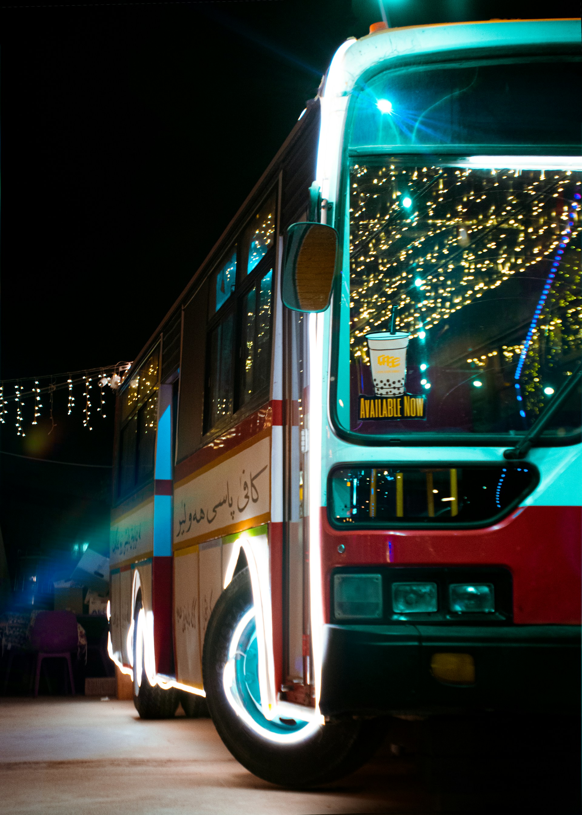 The Soundwave Express bus parked under a starry sky, its LED screen windows glowing vibrant colors as a DJ mixes inside.