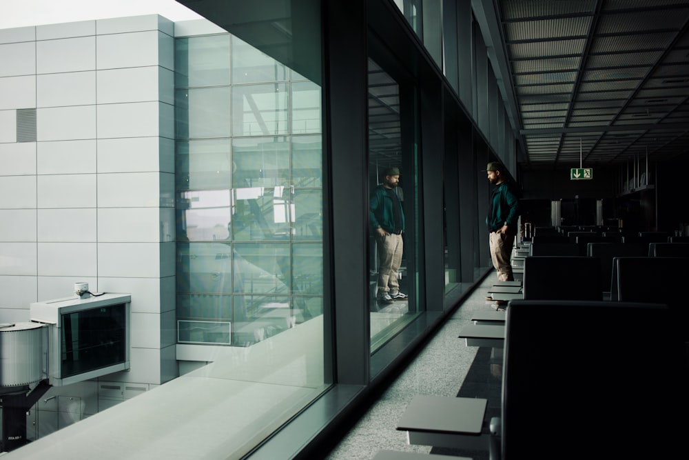 a couple of people standing next to each other near a window