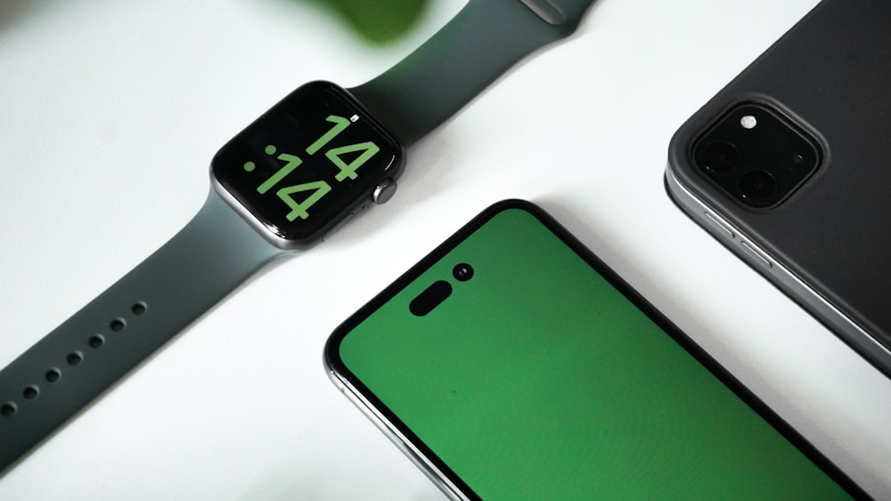 an apple watch with a green screen next to an iphone