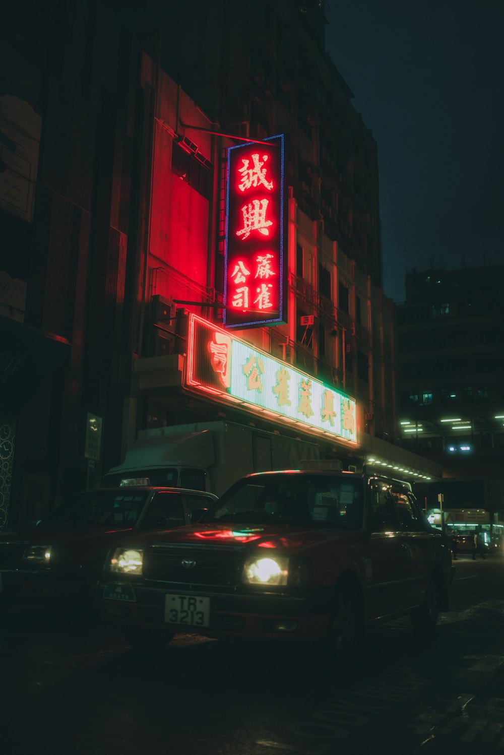 a city street at night with cars and neon signs