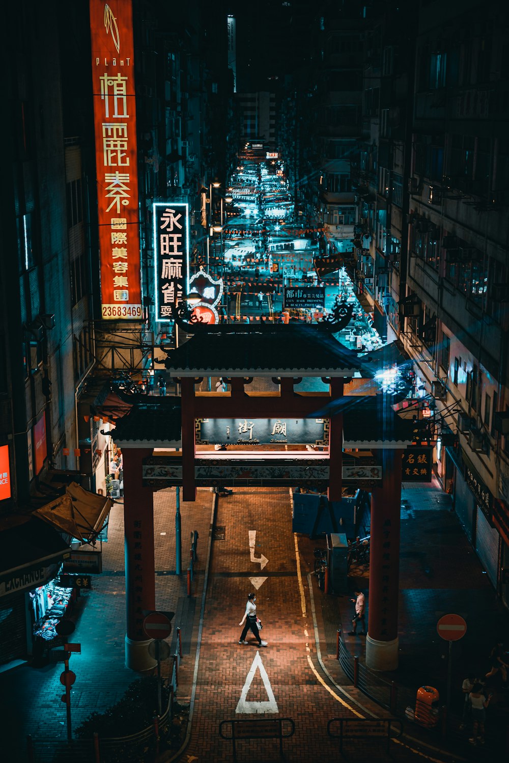 a city street at night with a person walking on the sidewalk