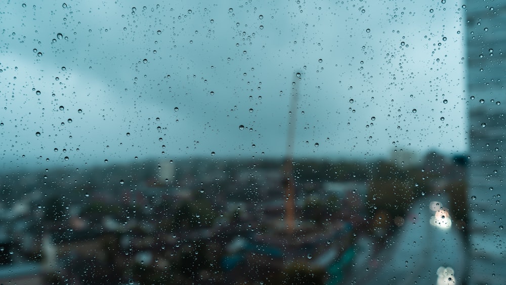 Una vista di una città attraverso una finestra coperta dalla pioggia