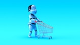 A humanoid robot with exaggerated features is pushing a small shopping cart against a bright blue background. The robot has a shiny, metallic finish with black and white segments, and the shopping cart has a red handle and frame.