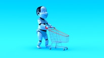 A humanoid robot with exaggerated features is pushing a small shopping cart against a bright blue background. The robot has a shiny, metallic finish with black and white segments, and the shopping cart has a red handle and frame.
