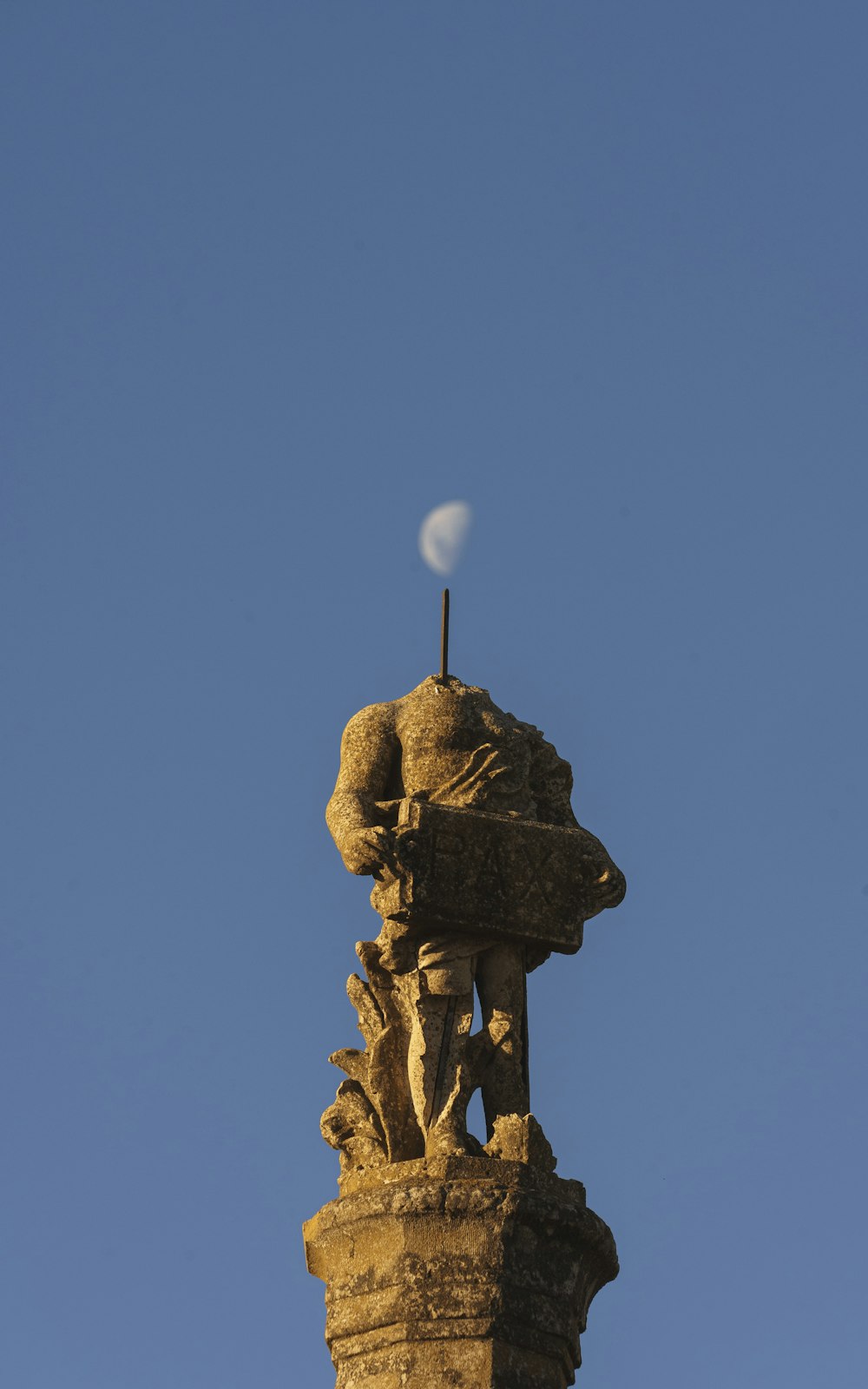 a statue on top of a building with a moon in the sky