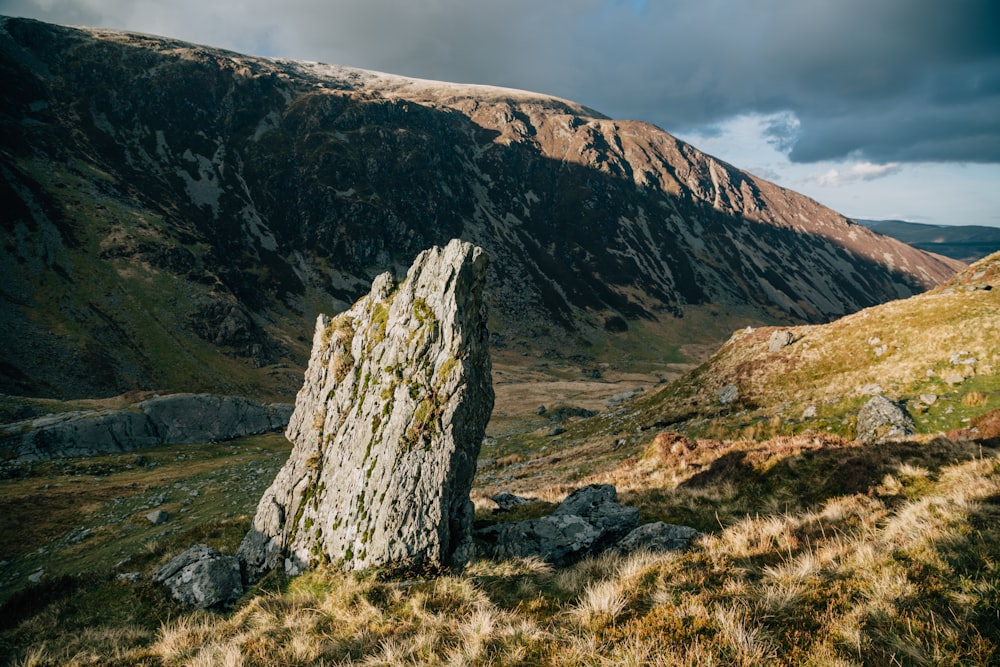 a large rock sitting on the side of a mountain