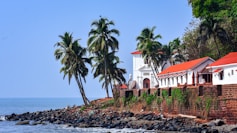 a white building with a red roof next to a body of water
